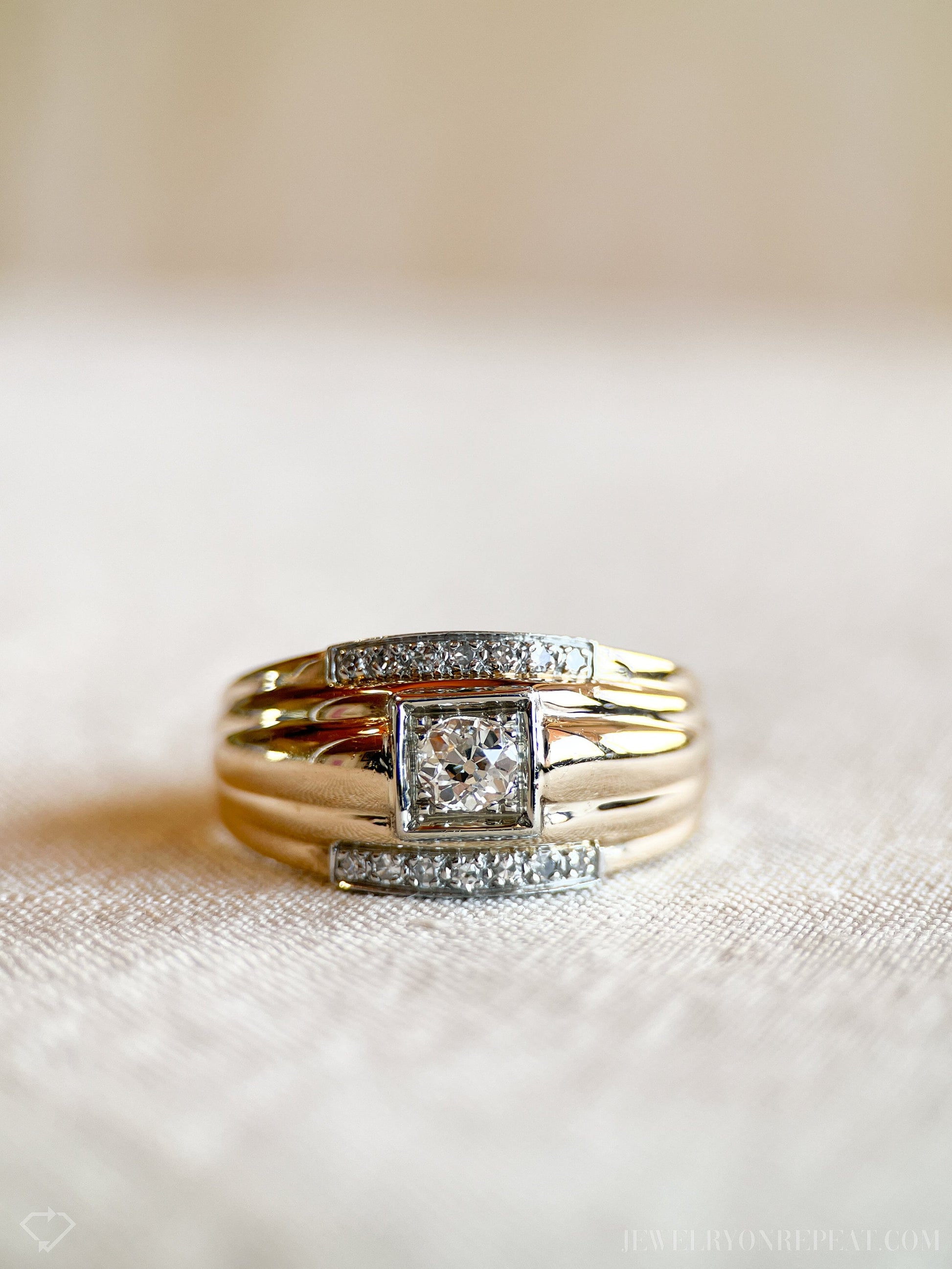 May include: A gold band ring with a square-shaped center stone and smaller diamonds set in the band.