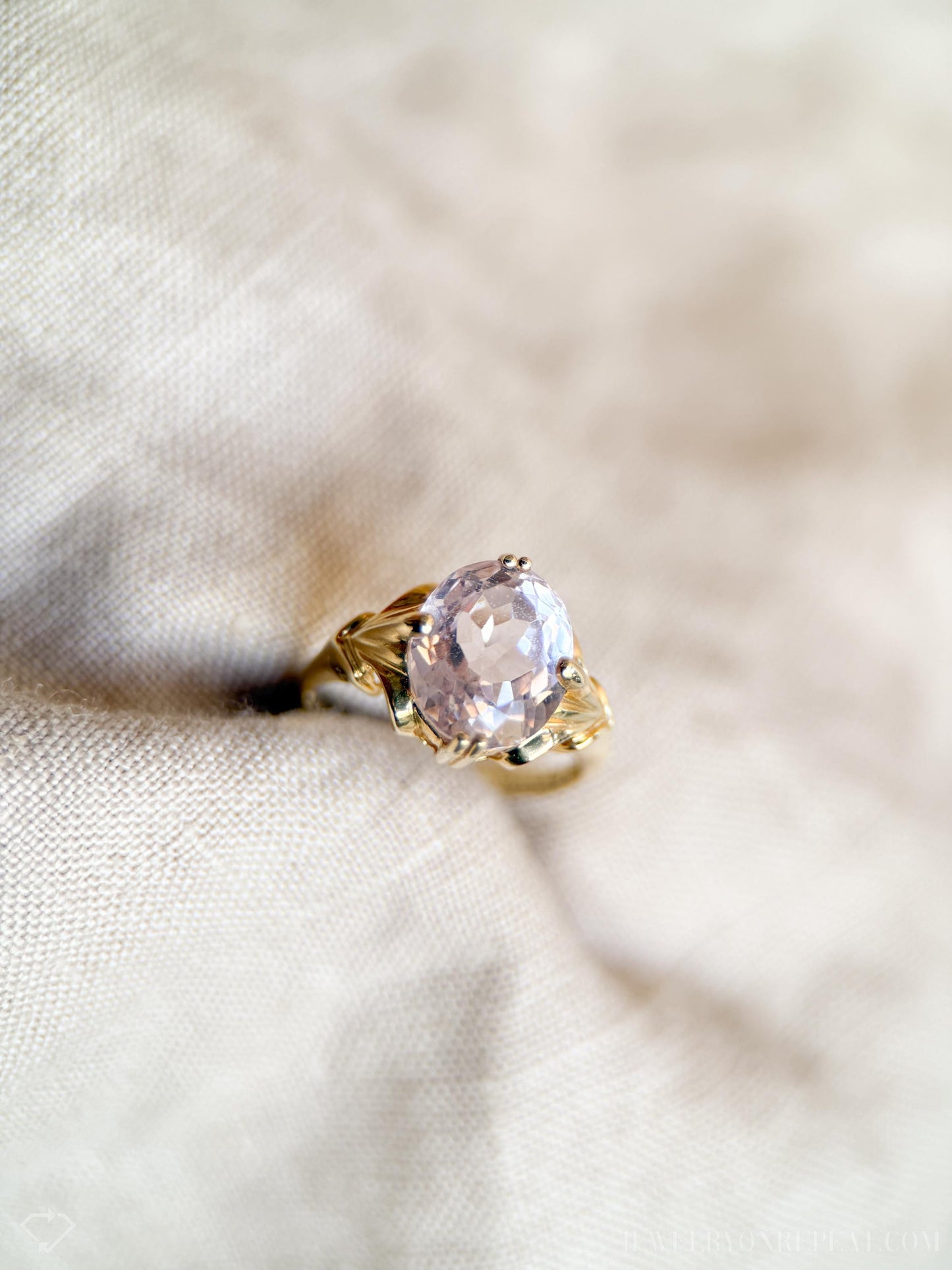 May include: A gold ring with a large, oval-shaped, light pink gemstone set in a delicate, leaf-shaped design.
