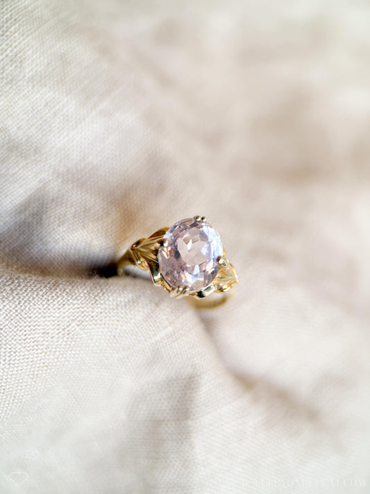 May include: A gold ring with a large, oval-shaped, light pink gemstone set in a delicate, leaf-shaped design.