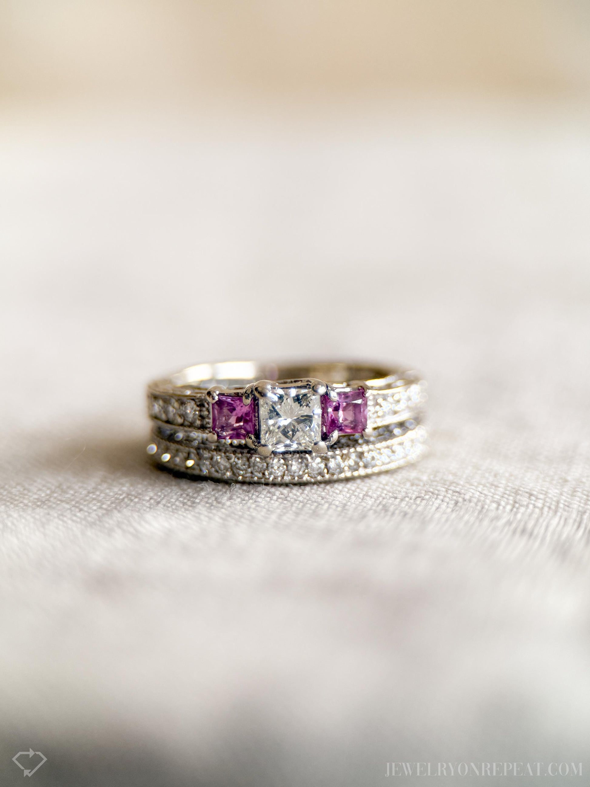 May include: A silver wedding band set with a large, clear, square-cut diamond and two smaller, square-cut purple gemstones.
