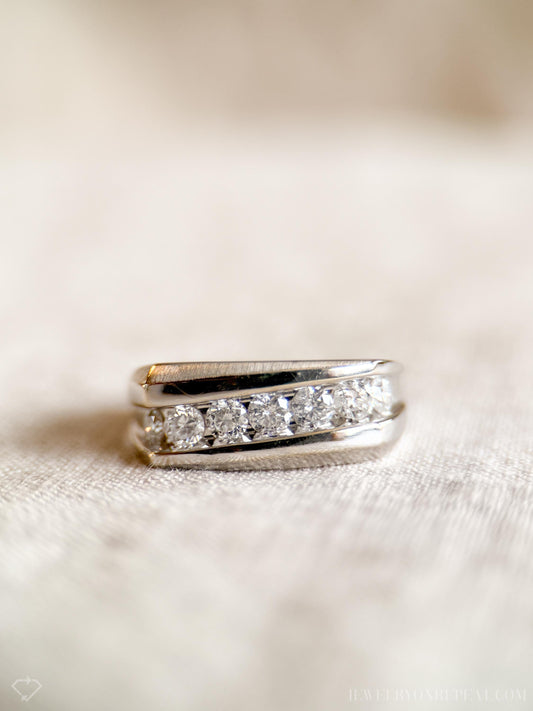 May include: A silver band with a row of small, round diamonds set in a channel setting.