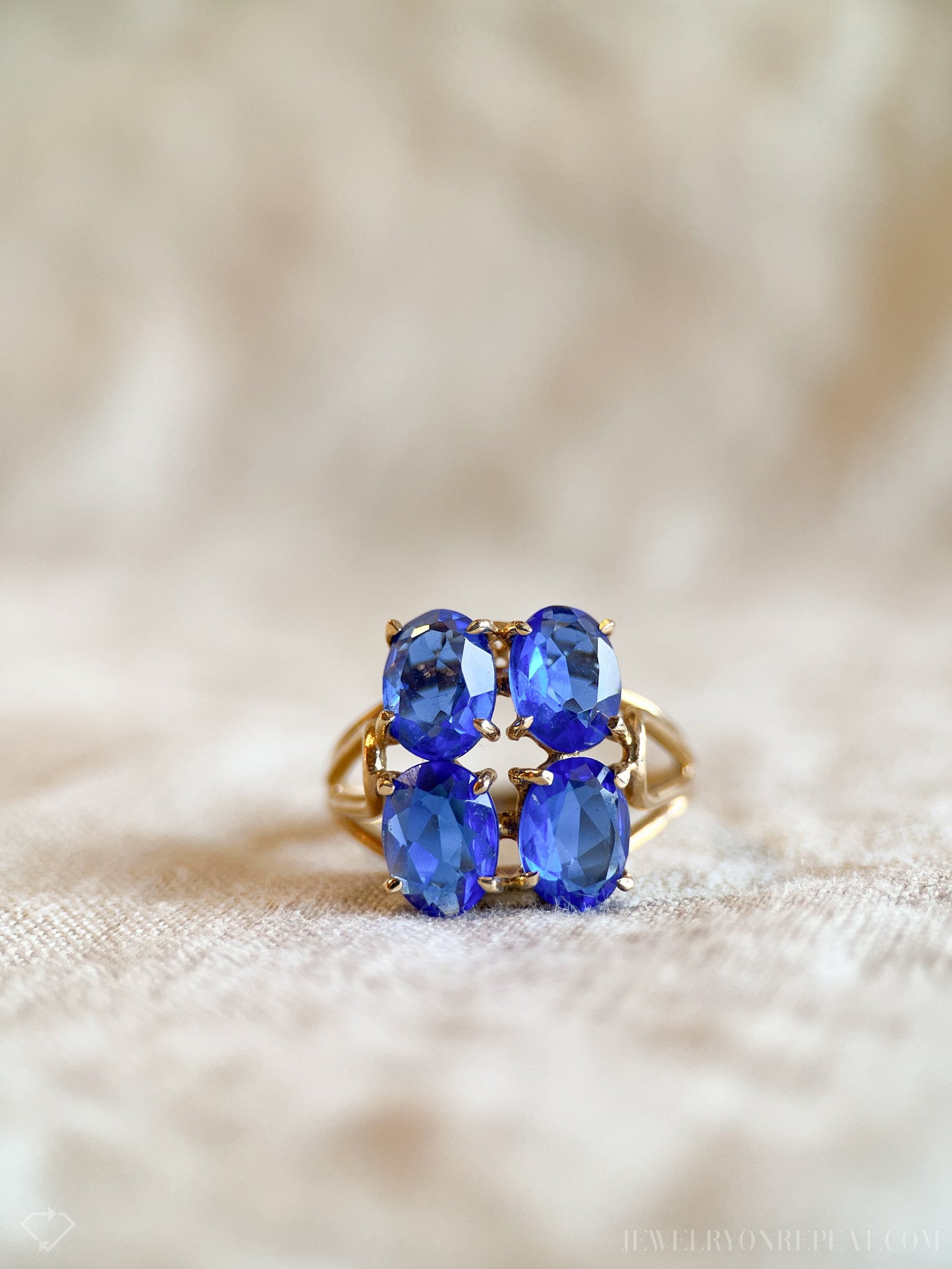 May include: A gold ring with four blue oval-shaped gemstones set in a cluster.