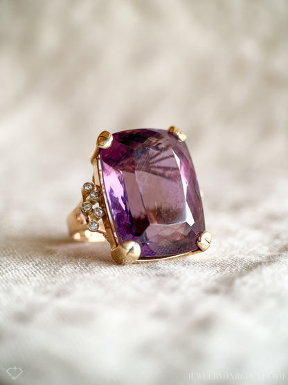 May include: A gold ring with a large, faceted amethyst gemstone and smaller diamonds set in the band.