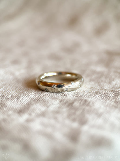 May include: A silver band ring with small diamonds set into the surface.