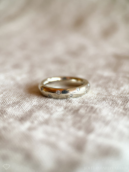 May include: A silver band ring with small diamonds set into the surface.