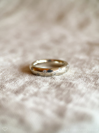 May include: A silver band ring with small diamonds set into the surface.